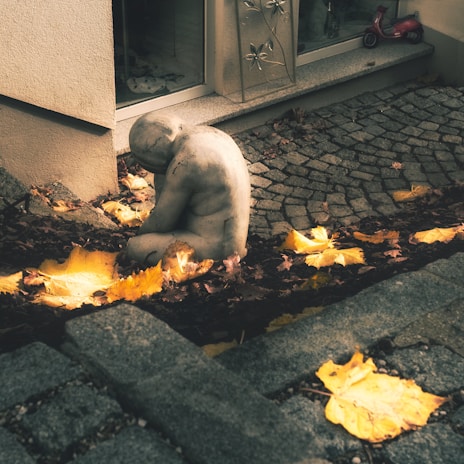 mobbing a teddy bear sitting on the ground in front of a building