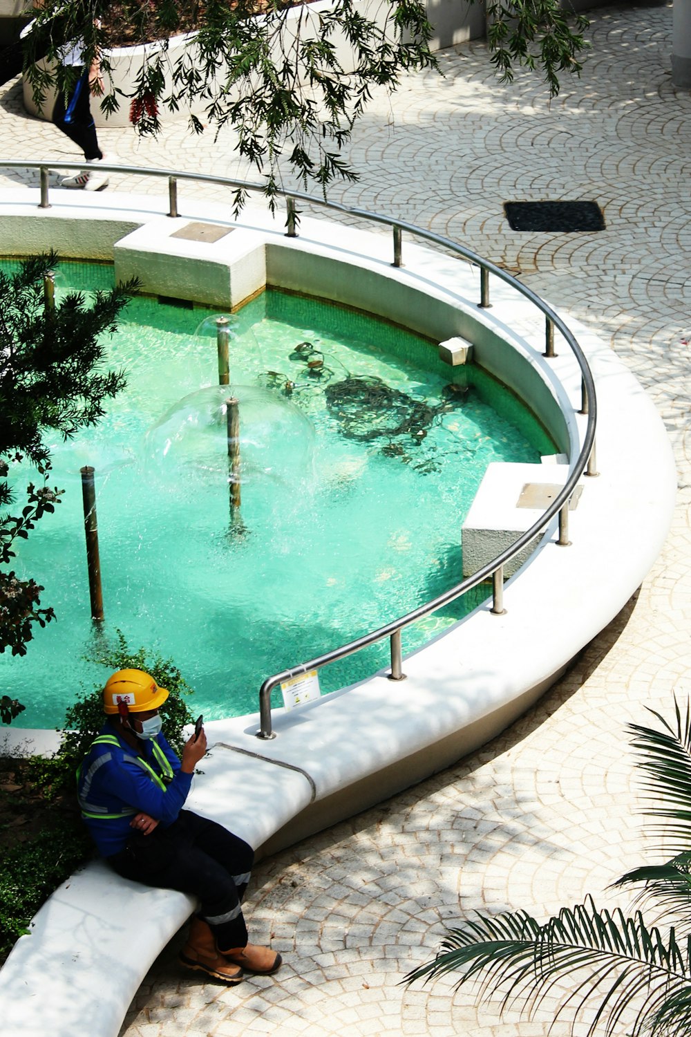 a man sitting on a bench next to a pool of water