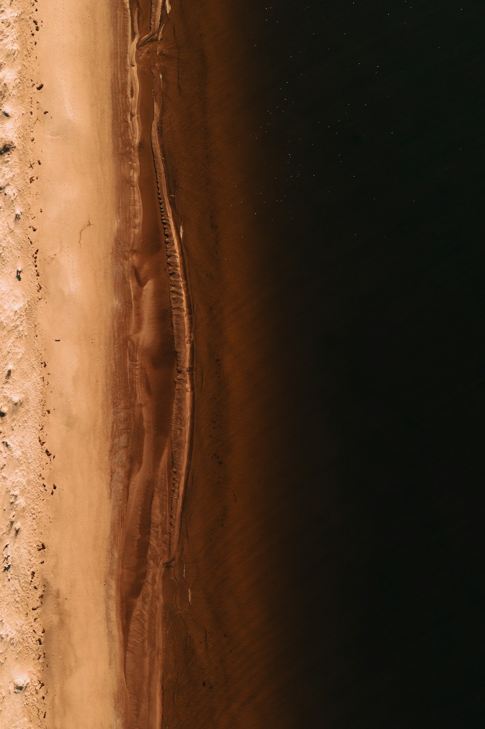 an aerial view of a sandy beach and a body of water