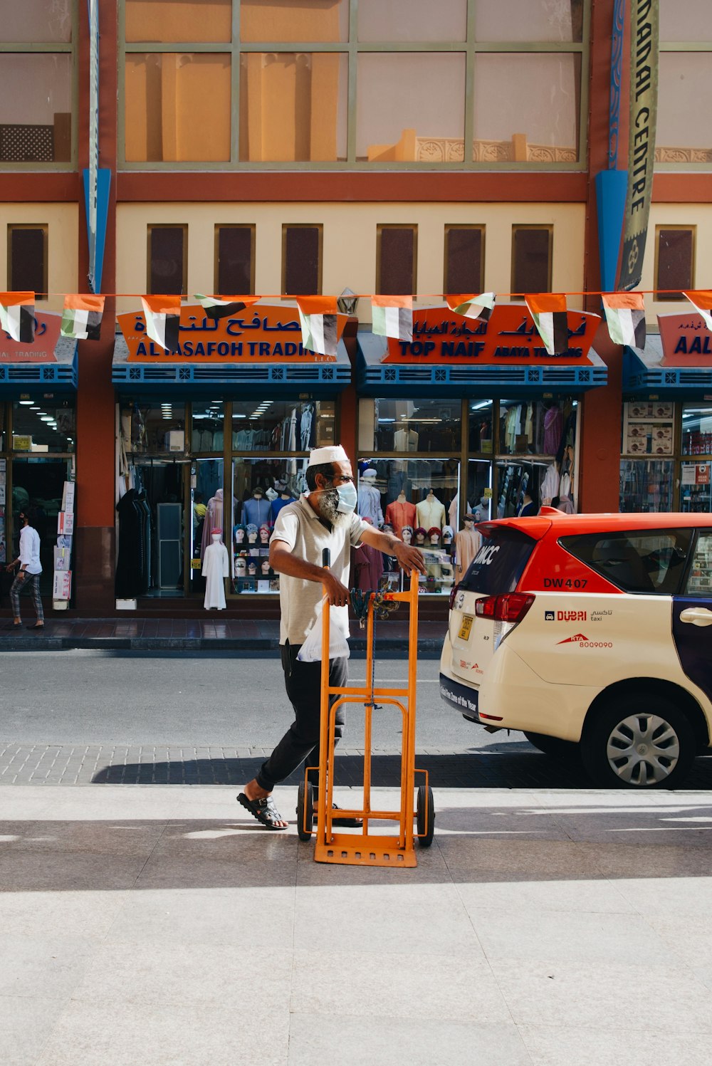a man walking down the street with a luggage cart