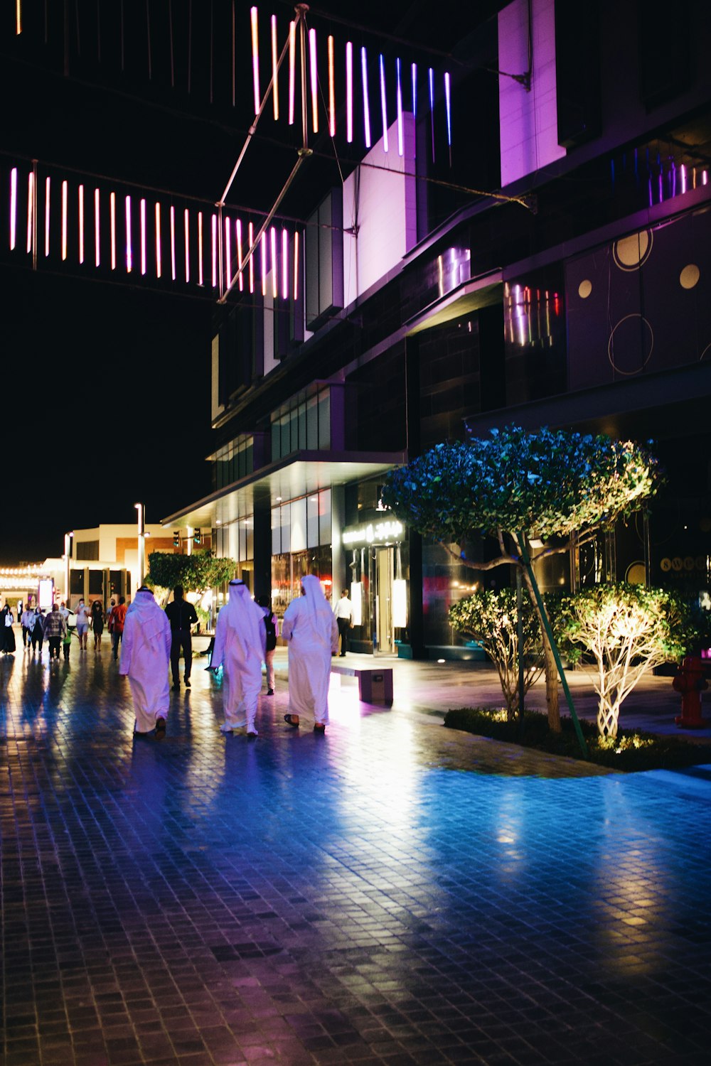 a group of people walking down a street at night