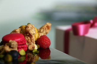 A close-up of a beautifully arranged gift box featuring macadamia nuts, cocoa beans, and a steaming cup of tea on a soft neutral background.