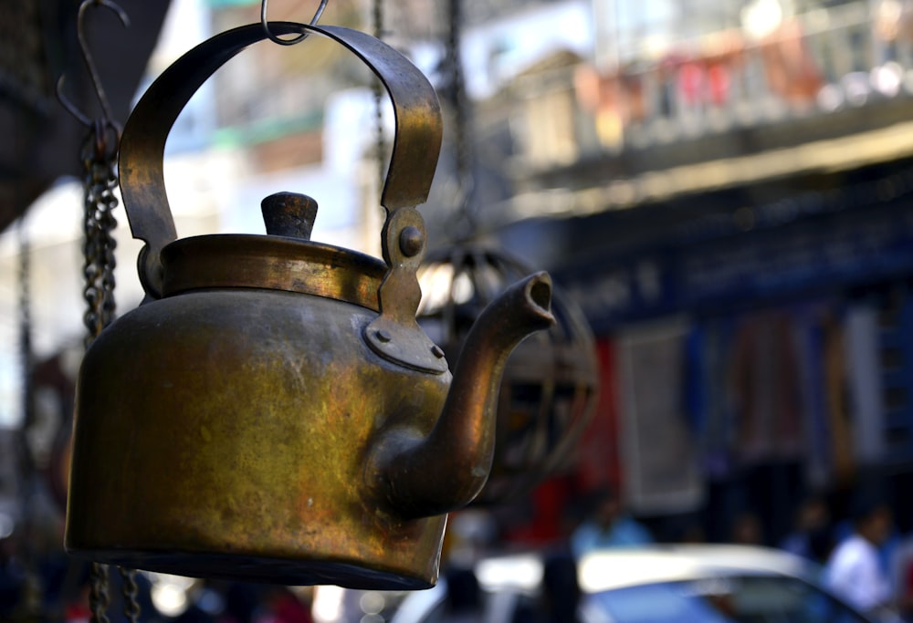 a tea kettle hanging from a chain on a street