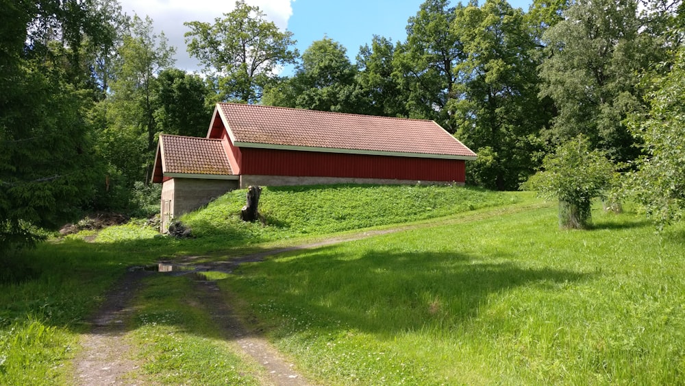 a red barn sitting on top of a lush green hillside