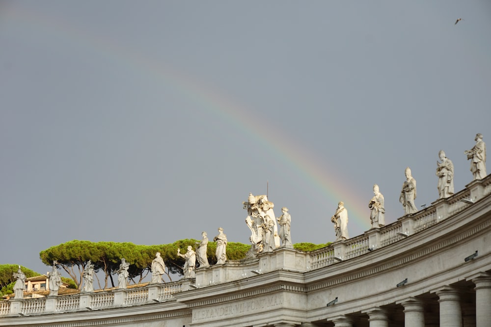 a rainbow in the sky over a building with statues