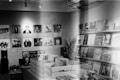 A vintage-style record store with walls adorned with music posters. Wooden crates in the center hold vinyl records, and shelves display various album covers. A small sound system setup is visible on a table, and a plant adds a touch of greenery to the scene.