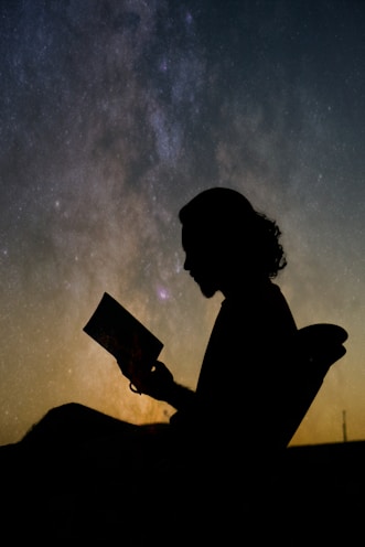 a silhouette of a person reading a book