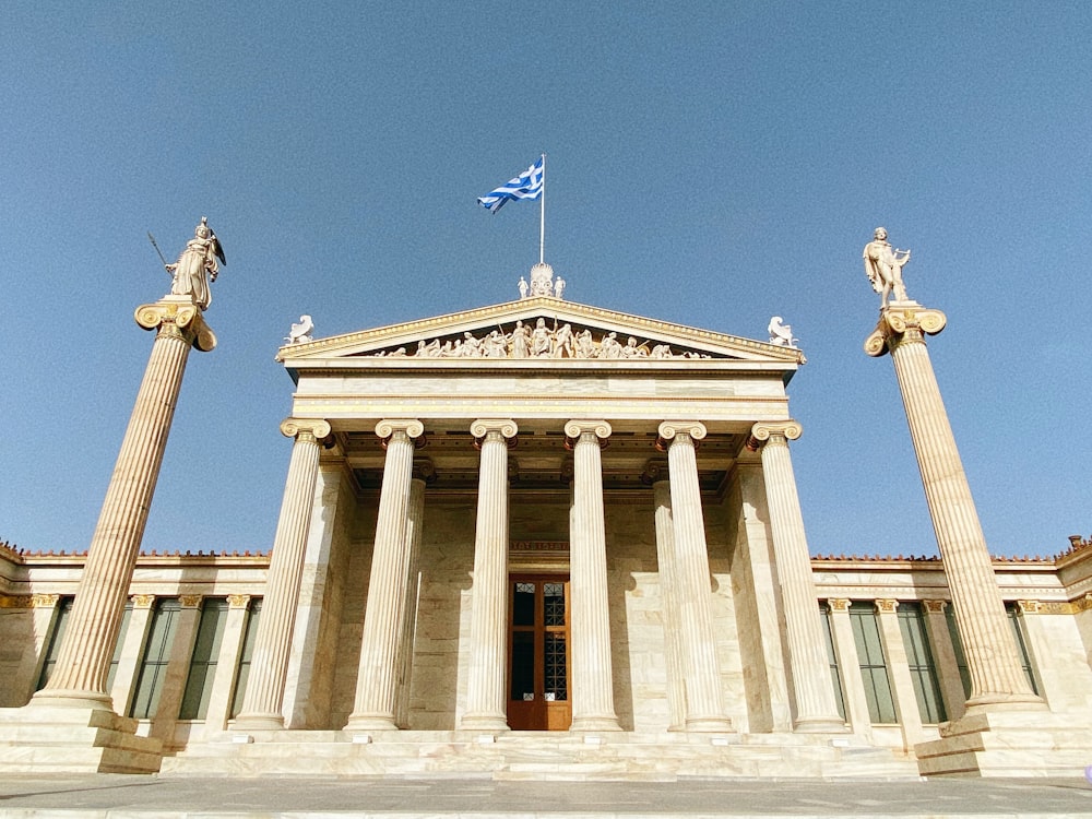 a building with columns and a flag on top of it