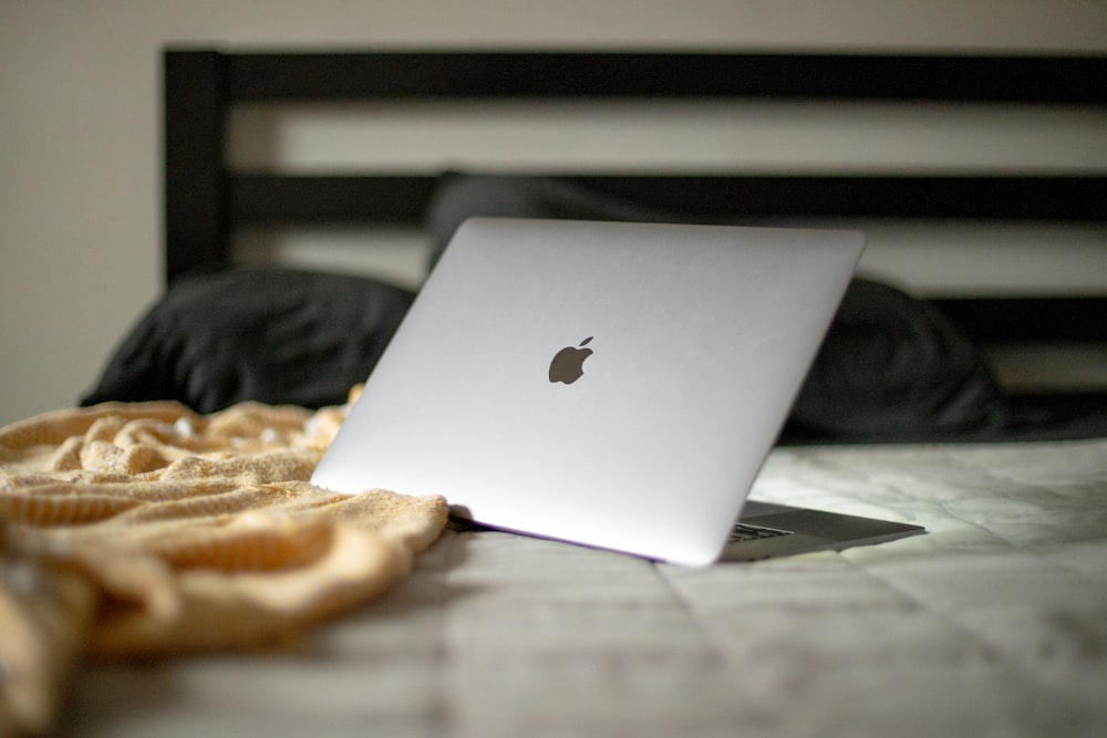 a white apple laptop sitting on a bed