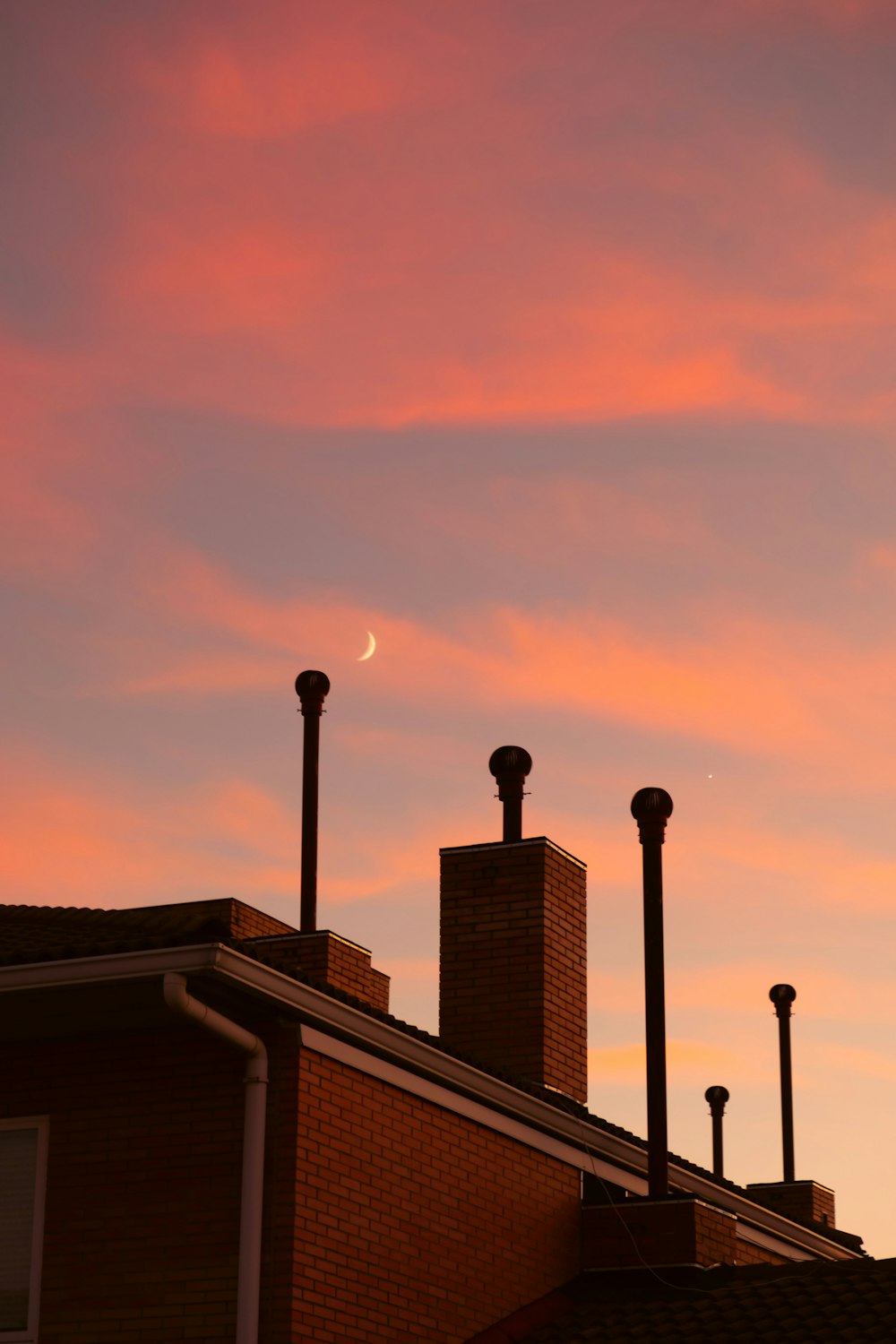 a pink sky with a crescent in the distance