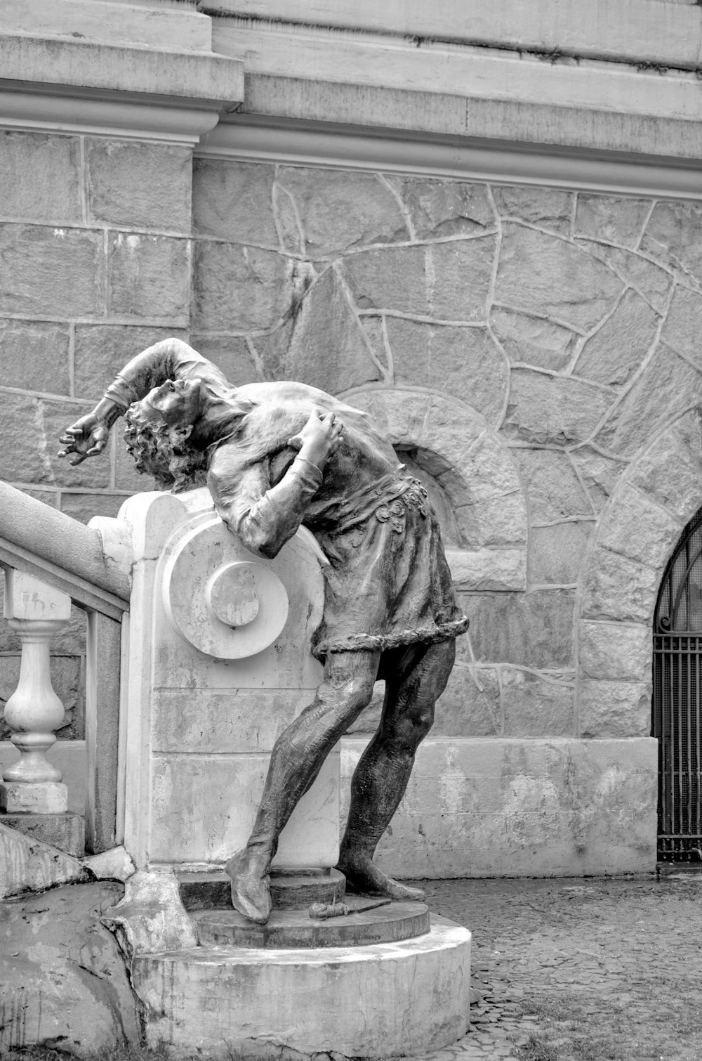 a statue of a man leaning on a fence