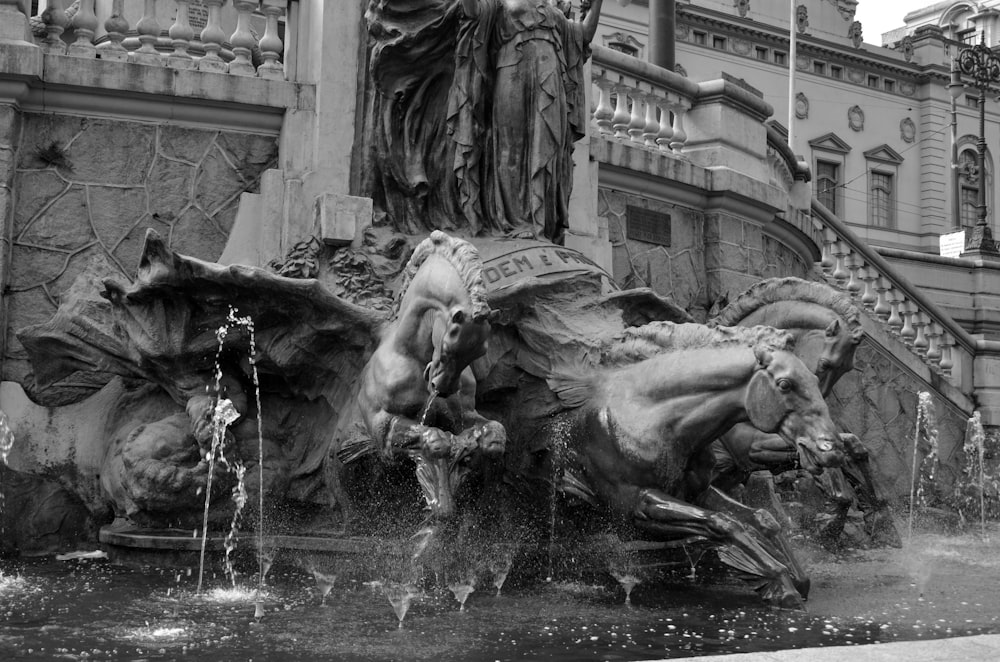 a black and white photo of a fountain in front of a building
