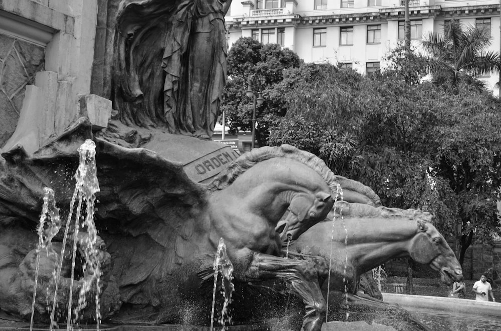 a black and white photo of a fountain with horses