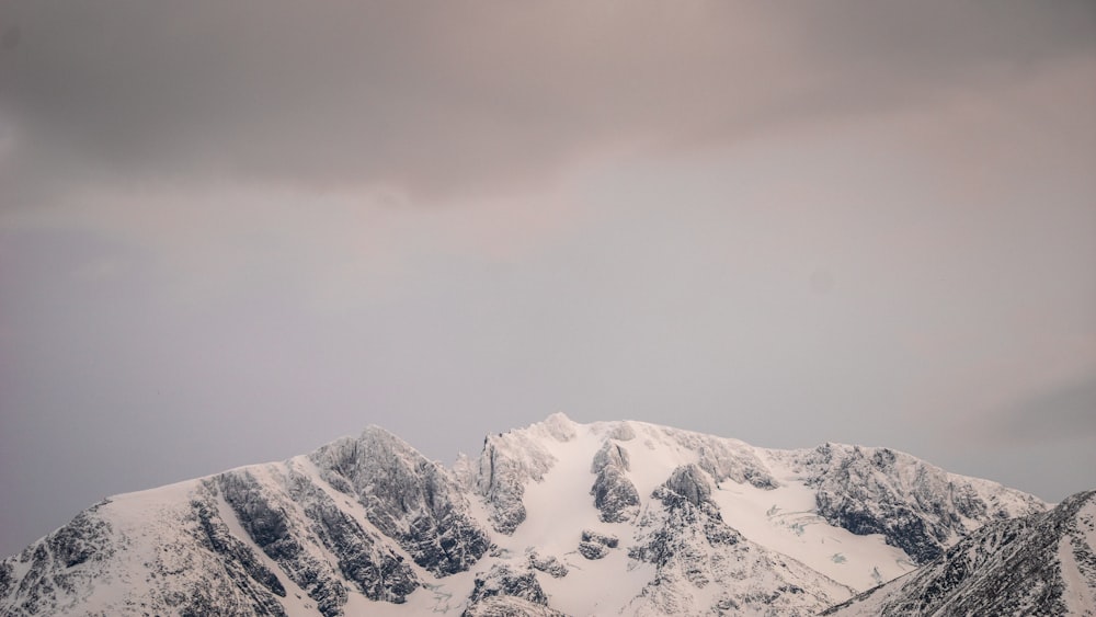 a mountain range covered in snow under a cloudy sky