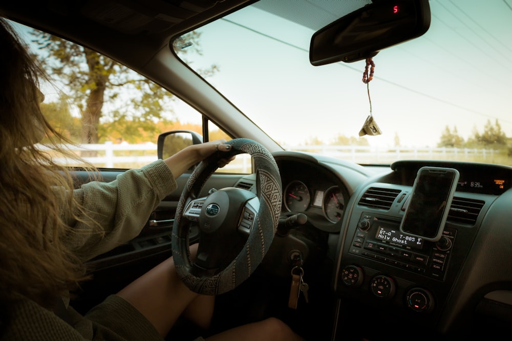 a woman driving a car with a steering wheel