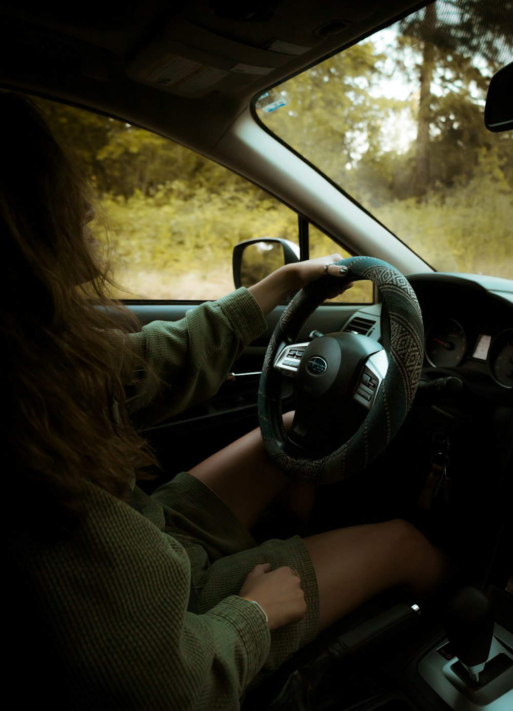 uma mulher que dirige um carro com um volante