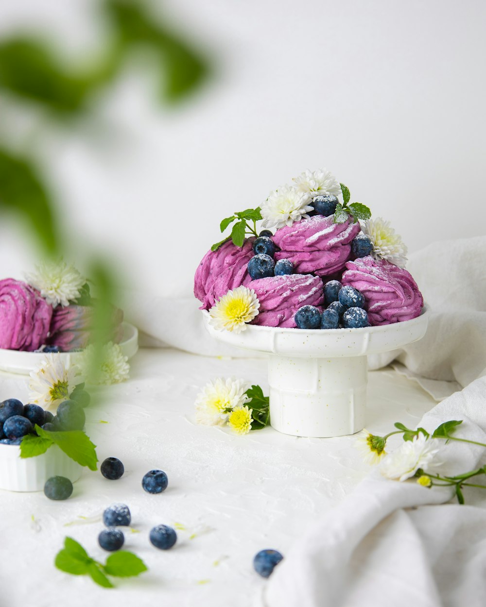 a cake with blueberries, raspberries, and daisies on a white
