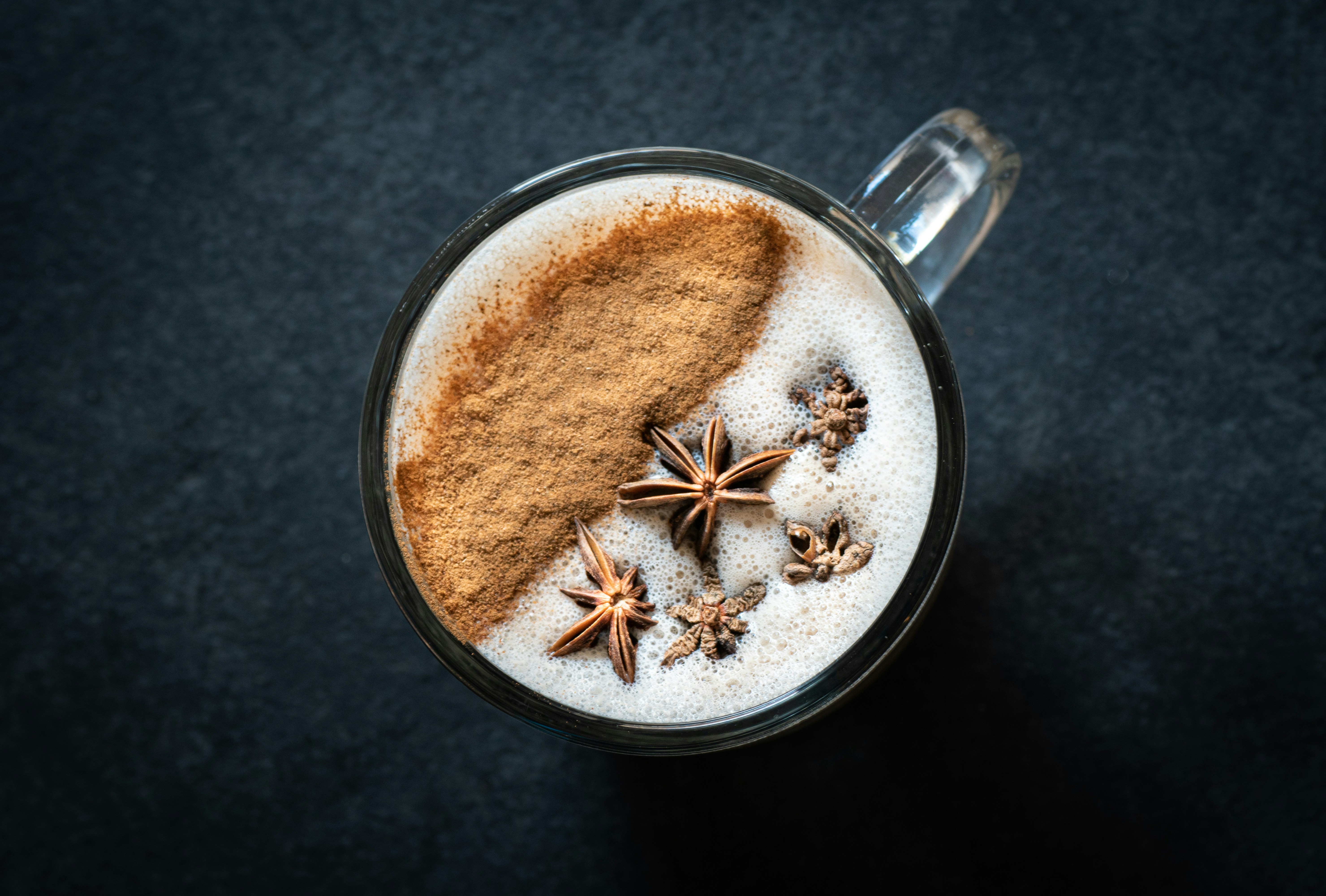 A cup of coffee with cinnamon and star anise on top