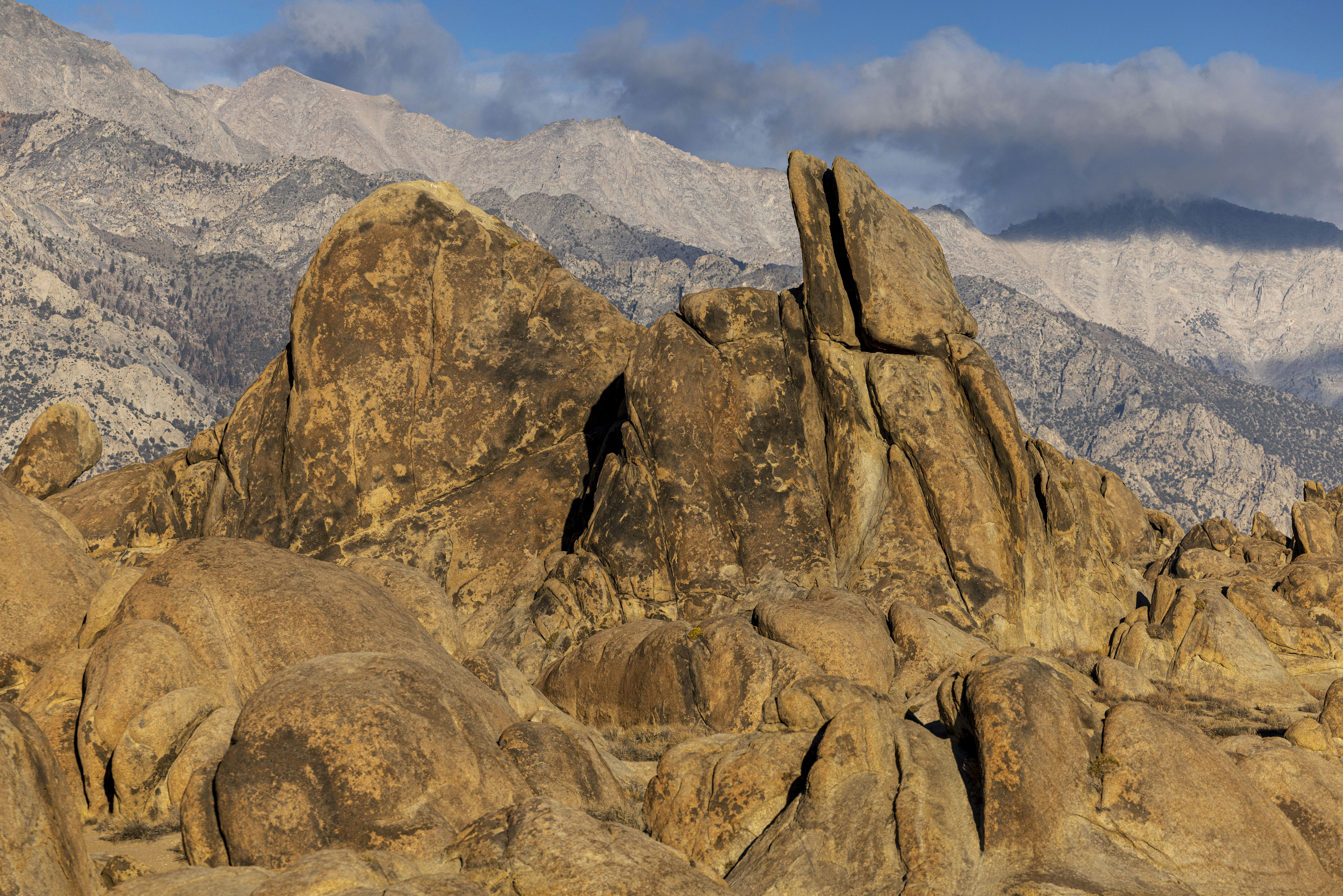 a large rock formation with mountains in the background
