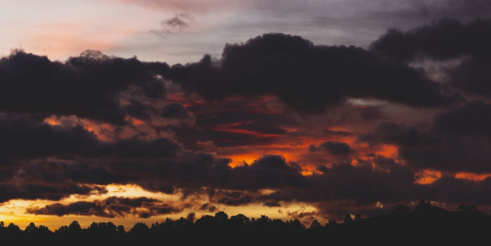 a plane flying through a cloudy sky at sunset