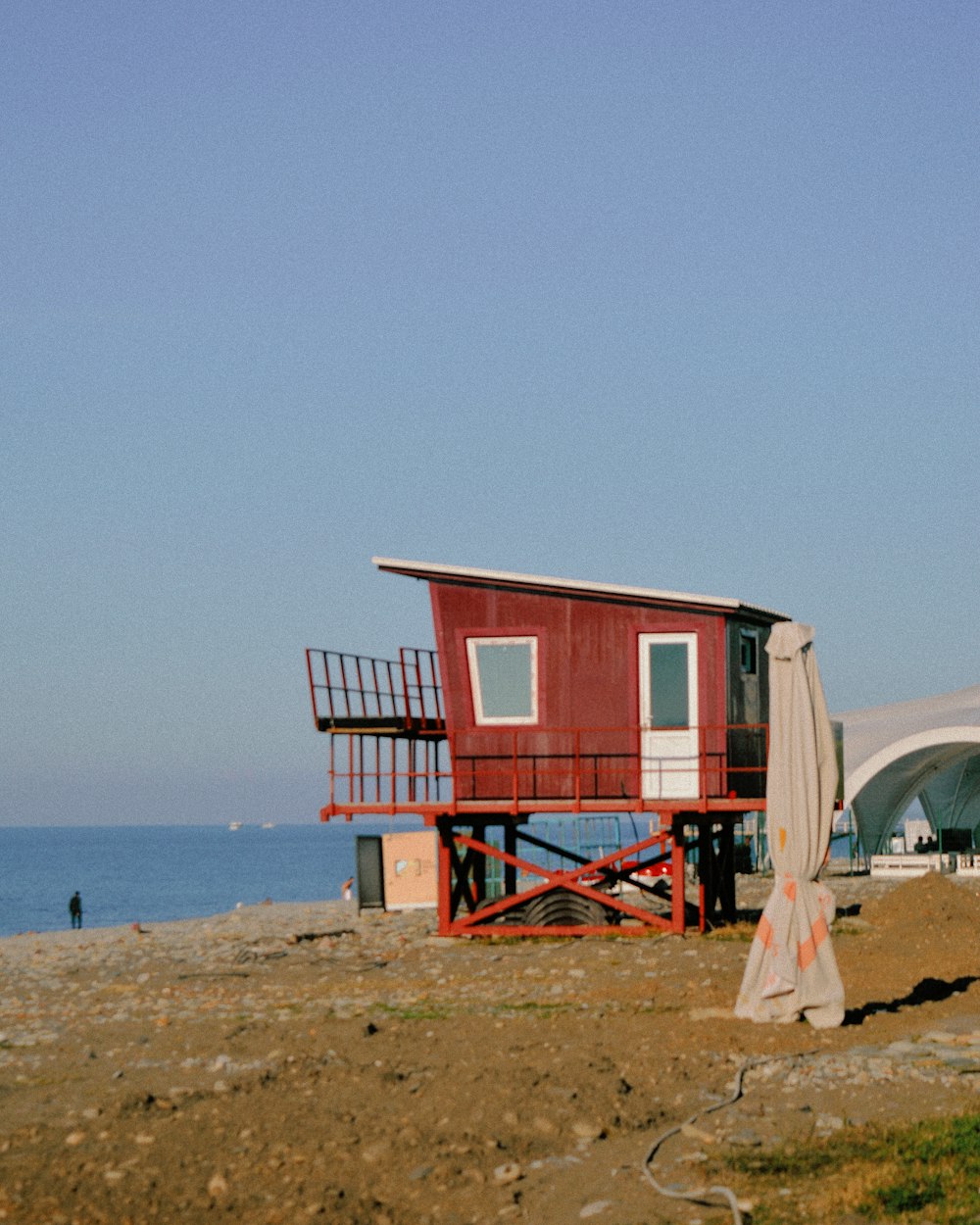 Una casa rossa seduta sulla cima di una spiaggia vicino all'oceano