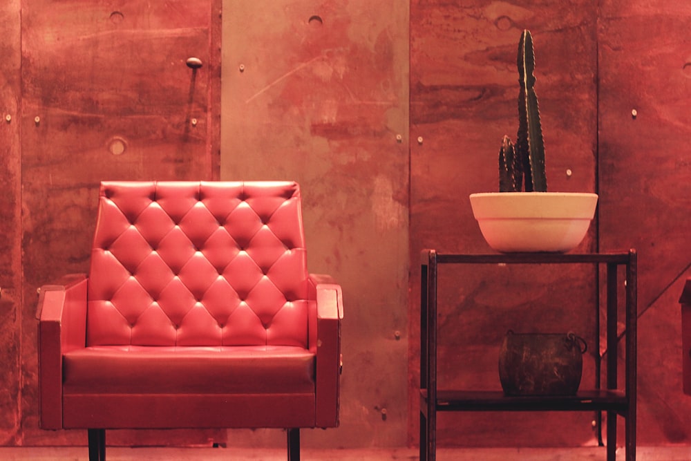 a red chair sitting next to a potted cactus