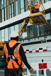 a man in an orange safety vest standing in front of a building