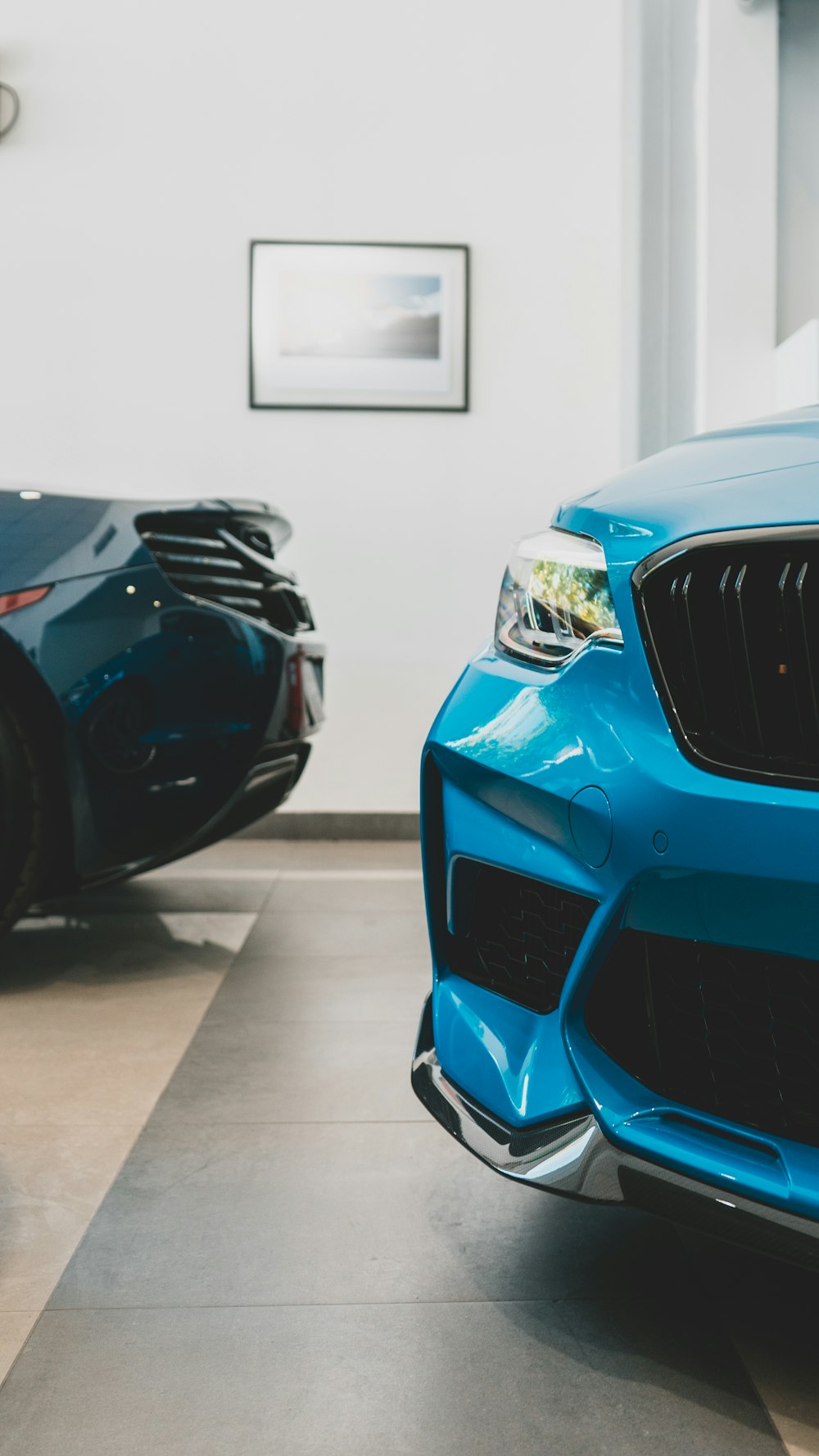 Un'auto blu parcheggiata in un garage accanto a un'altra auto blu