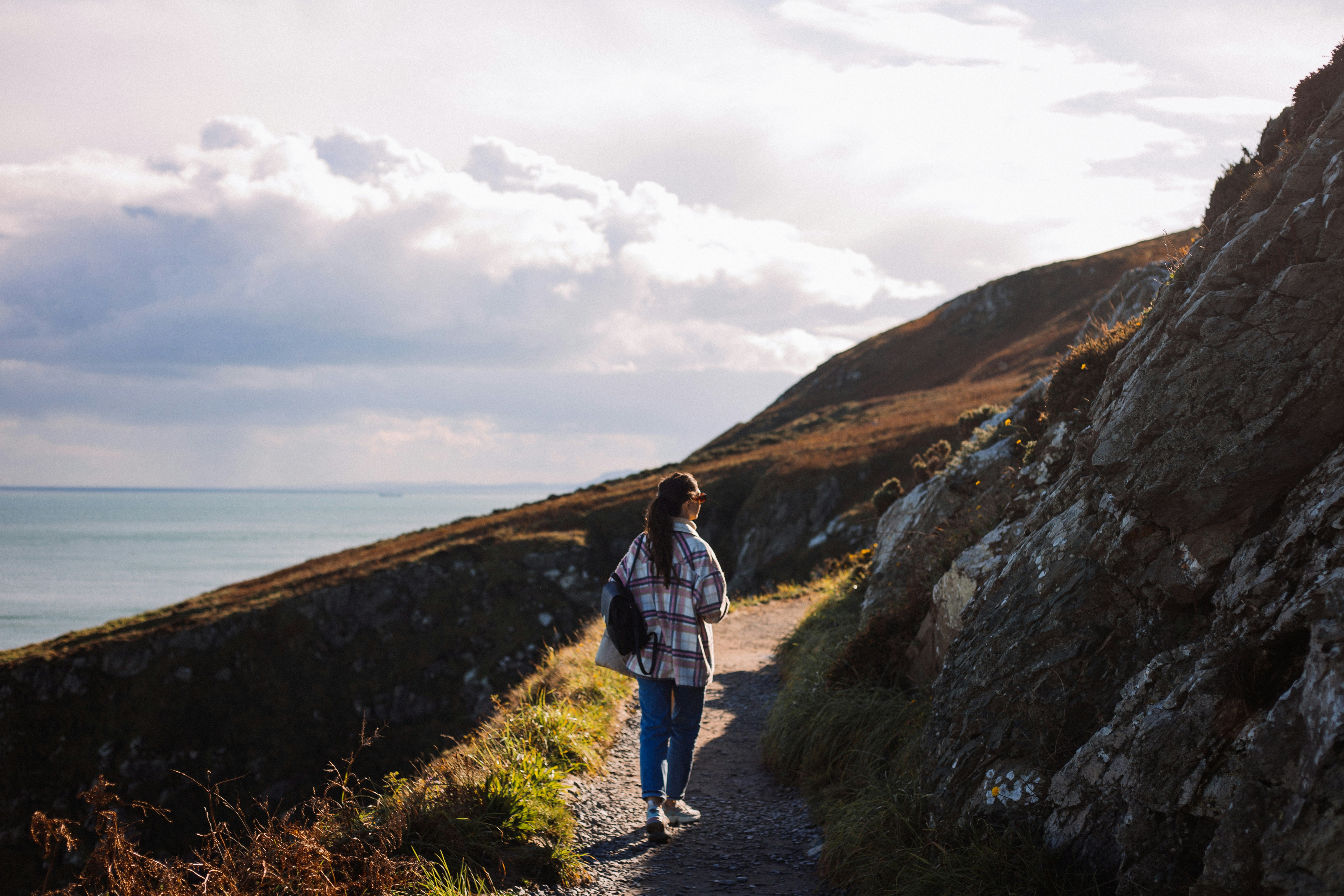 a person walking down a path next to the ocean