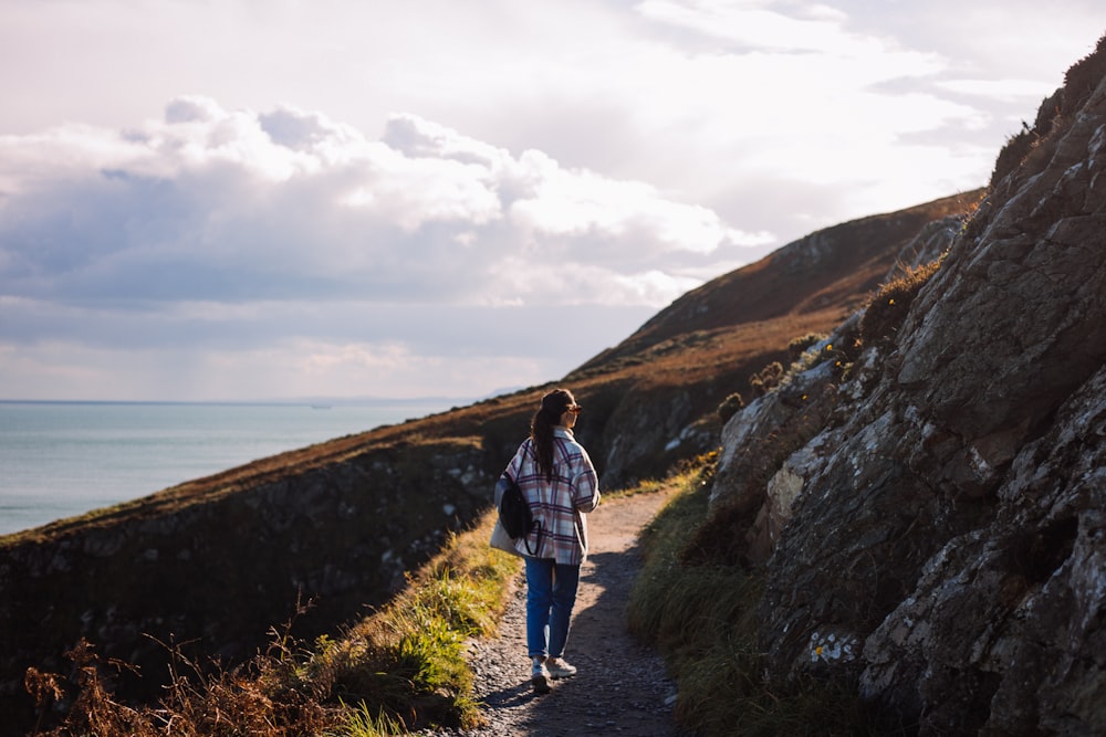 a person walking down a path next to the ocean