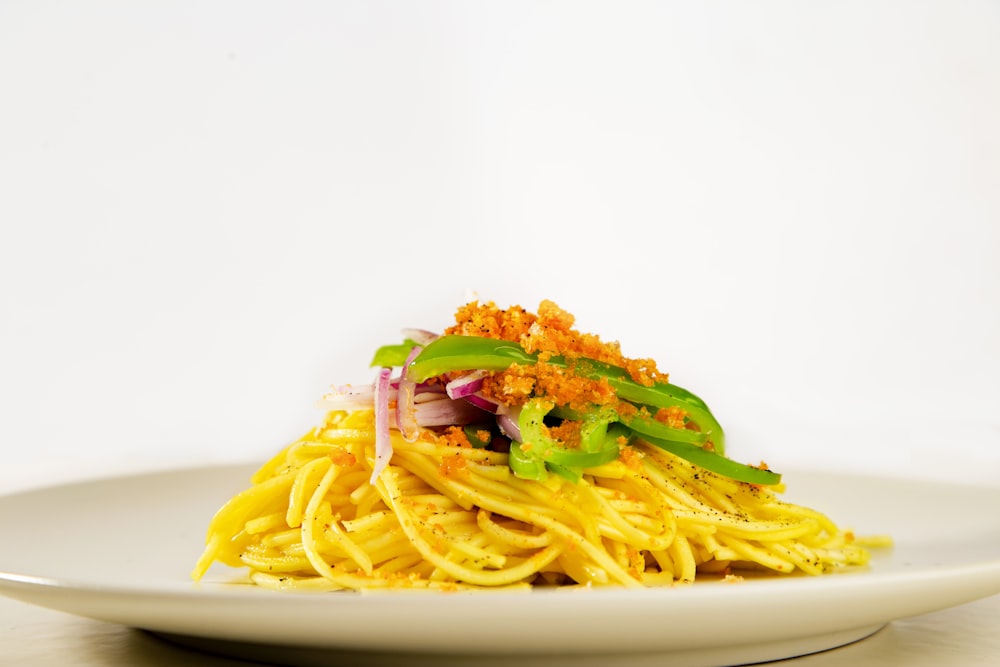a white plate topped with spaghetti and vegetables
