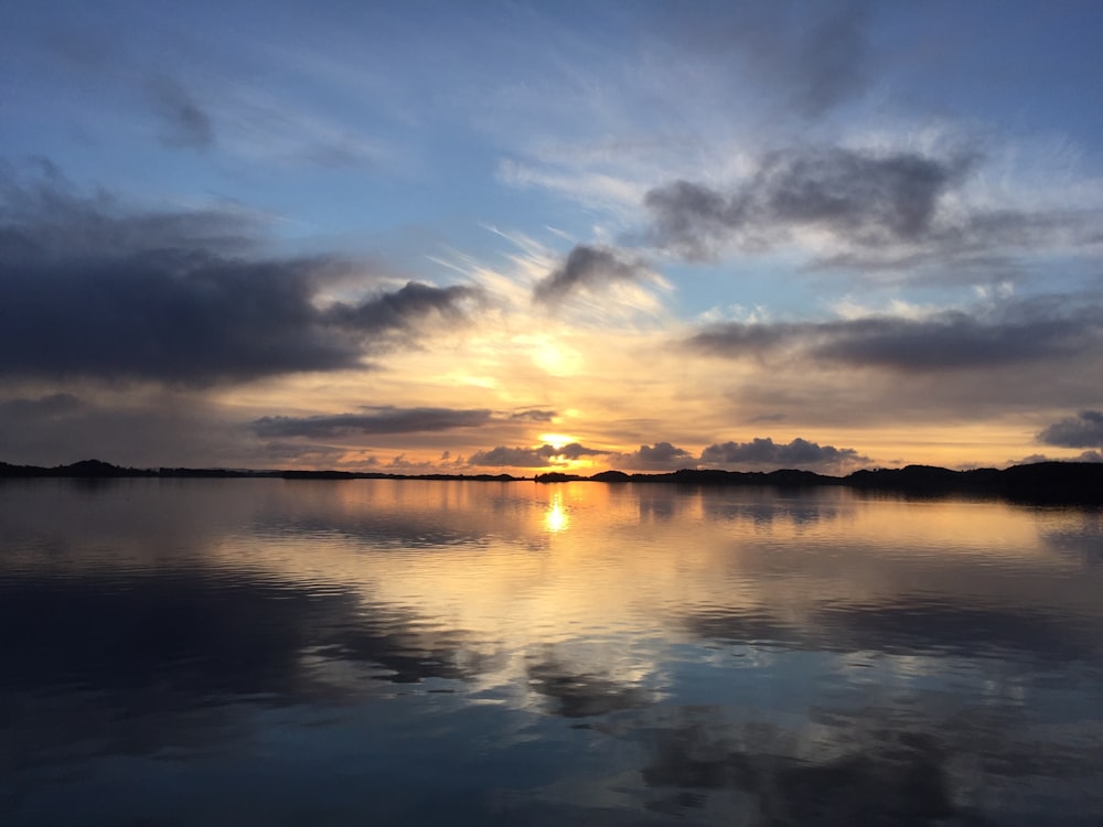 the sun is setting over a calm lake