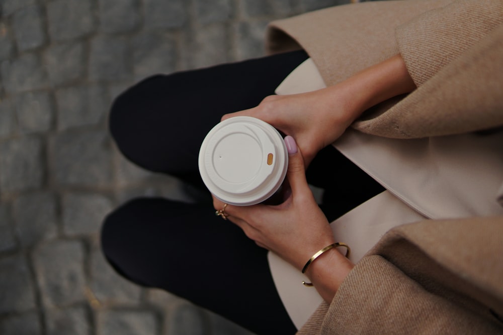 Una mujer sosteniendo una taza de café en sus manos