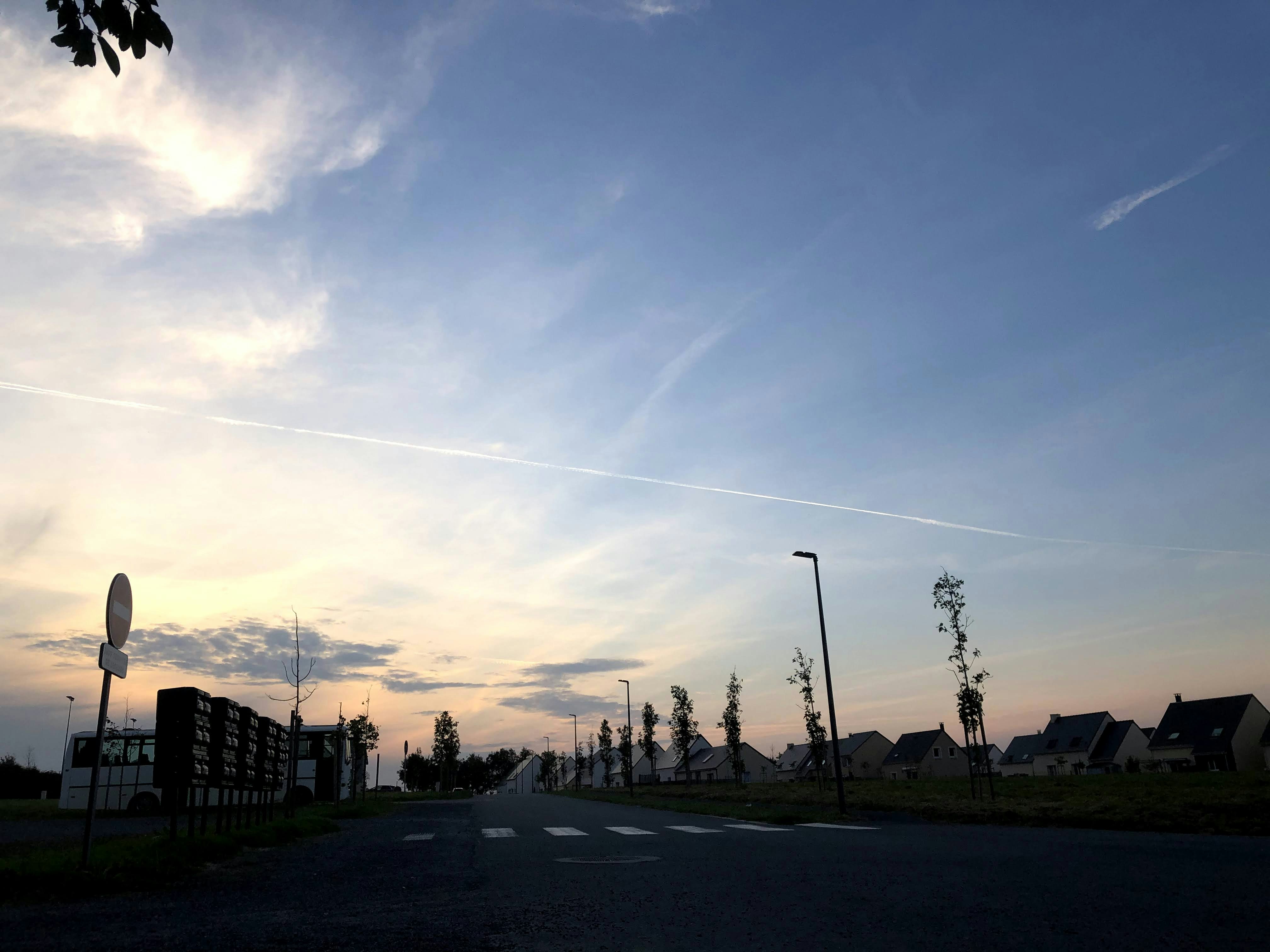 A road leading towards houses at dusk with clouds.