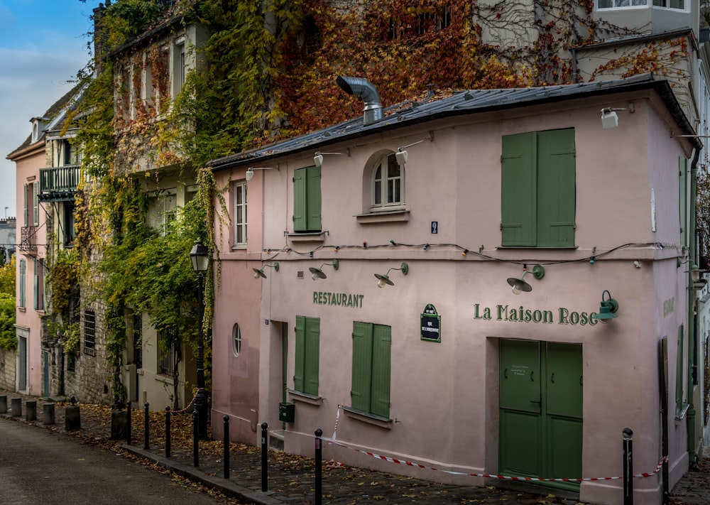 a pink building with green shutters next to a street