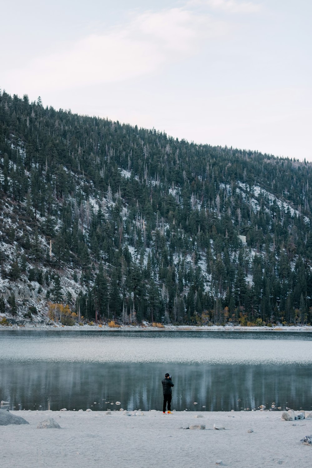 a person standing in the snow near a body of water