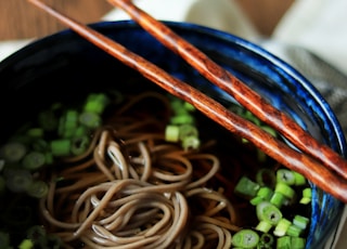 two chopsticks are sticking out of a bowl of noodles