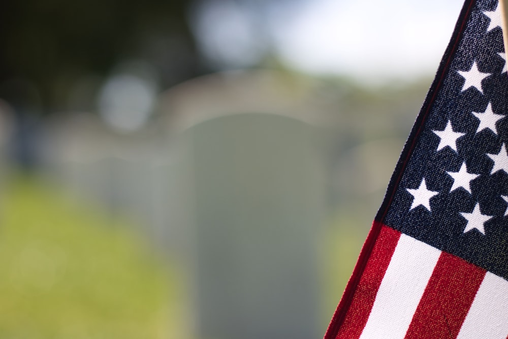 a close up of an american flag with a cemetery in the background