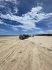 a couple of trucks parked on top of a sandy beach