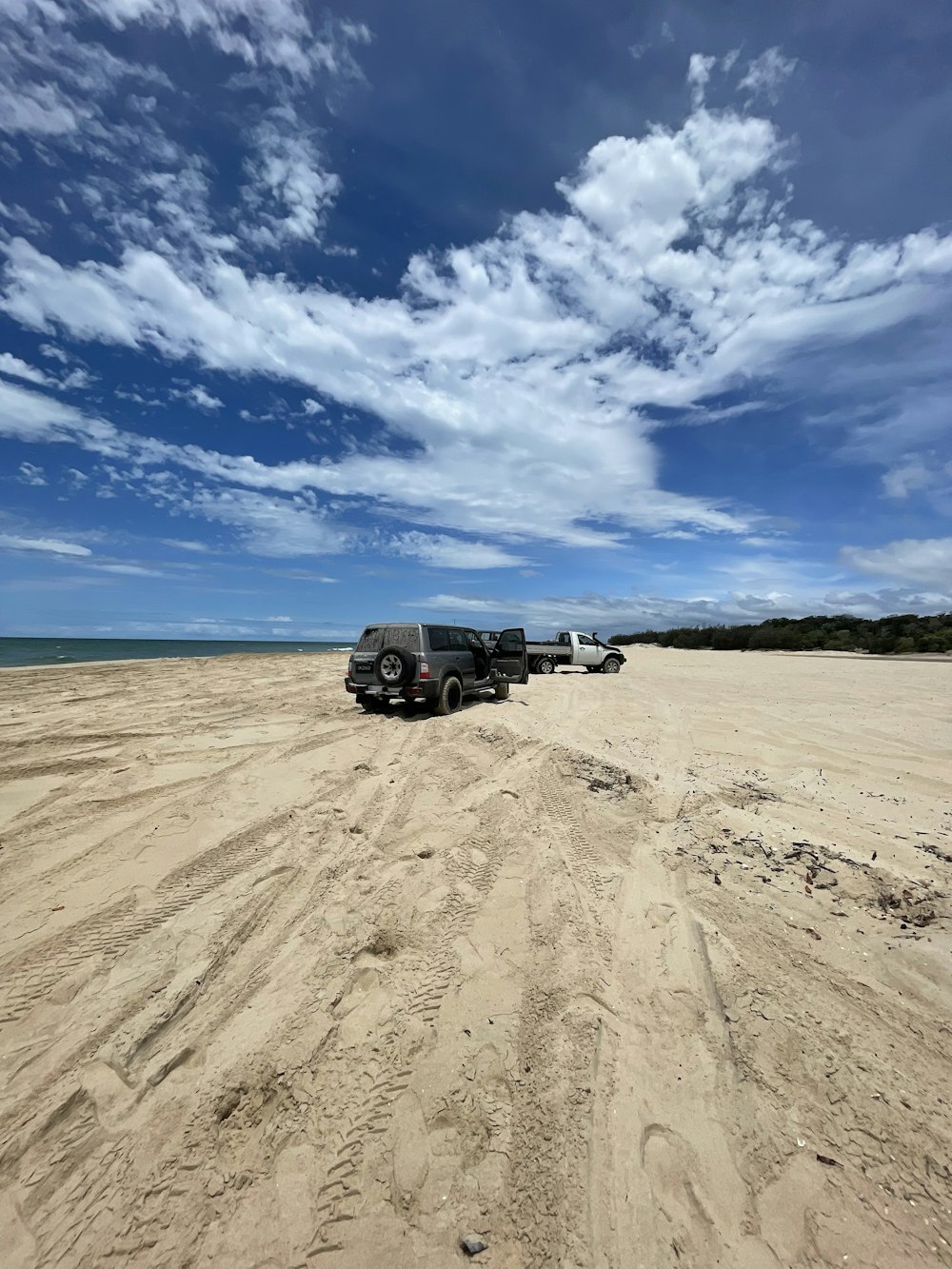 a couple of trucks parked on top of a sandy beach