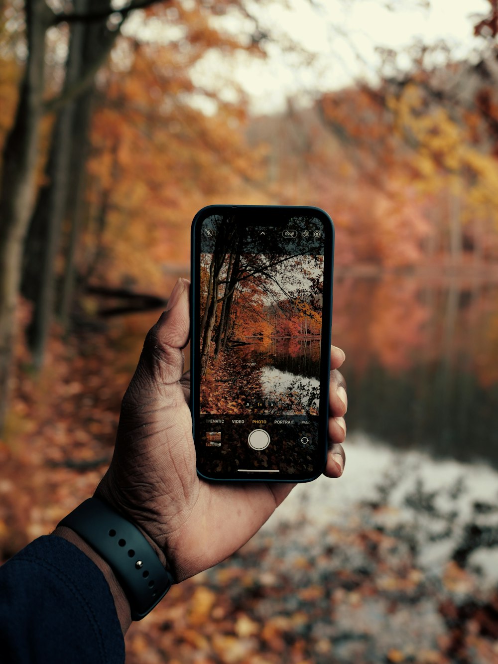 a person holding up a cell phone in front of a river