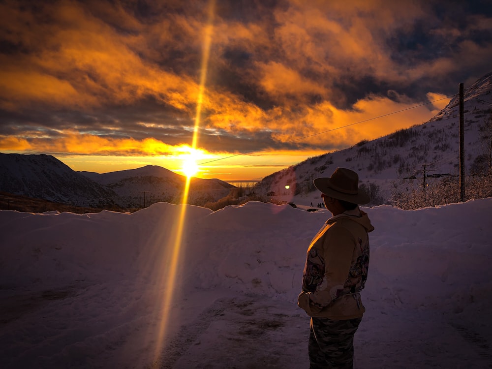 a man standing in the snow at sunset