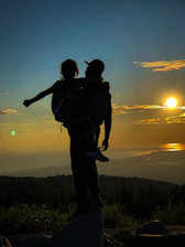 A minimalist black and white image capturing a father and daughter silhouette at sunset.