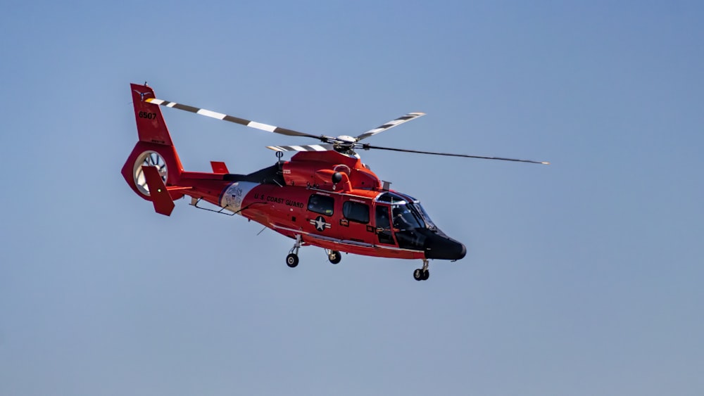 a red helicopter flying through a blue sky