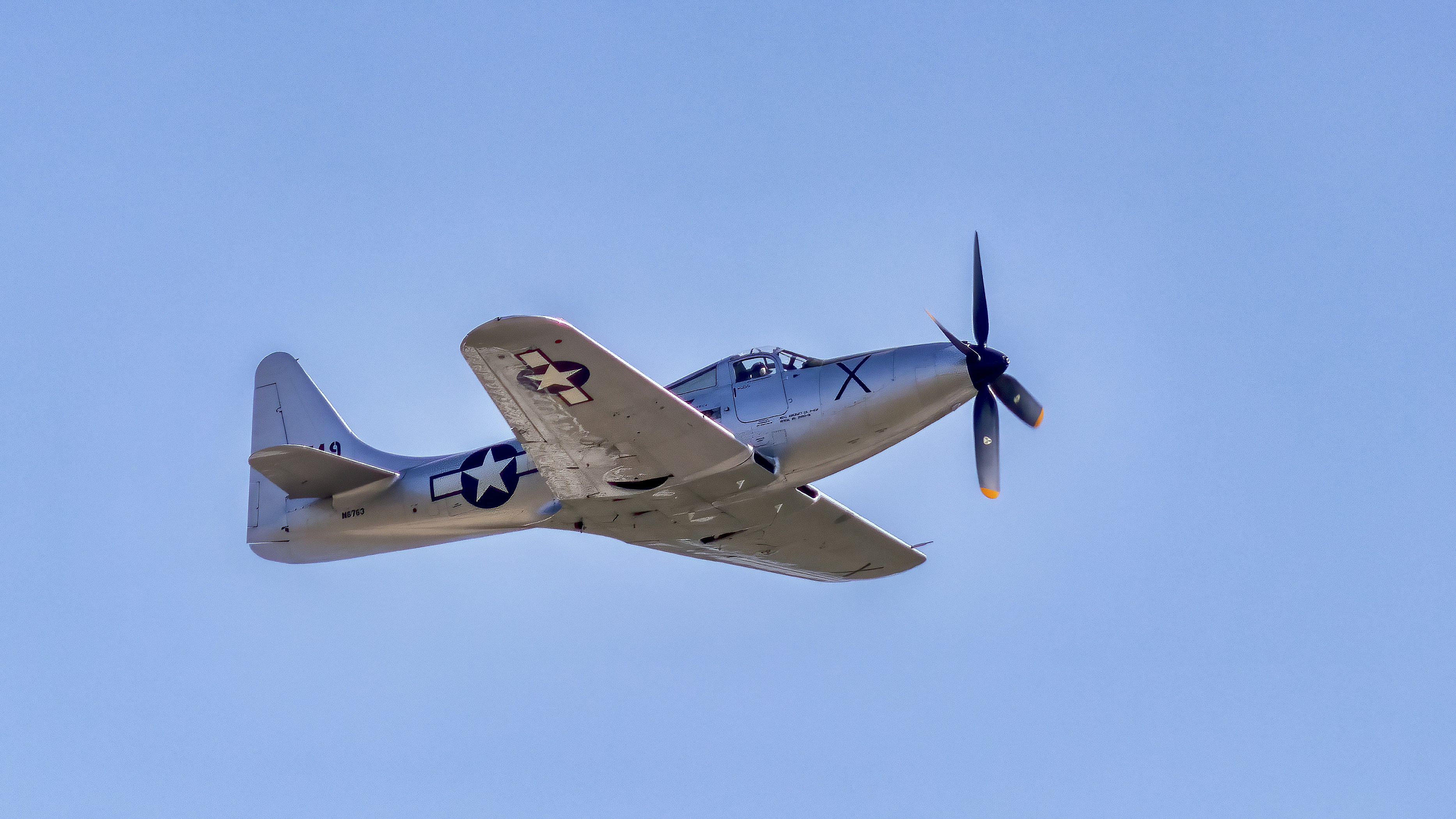 a small airplane flying through a blue sky