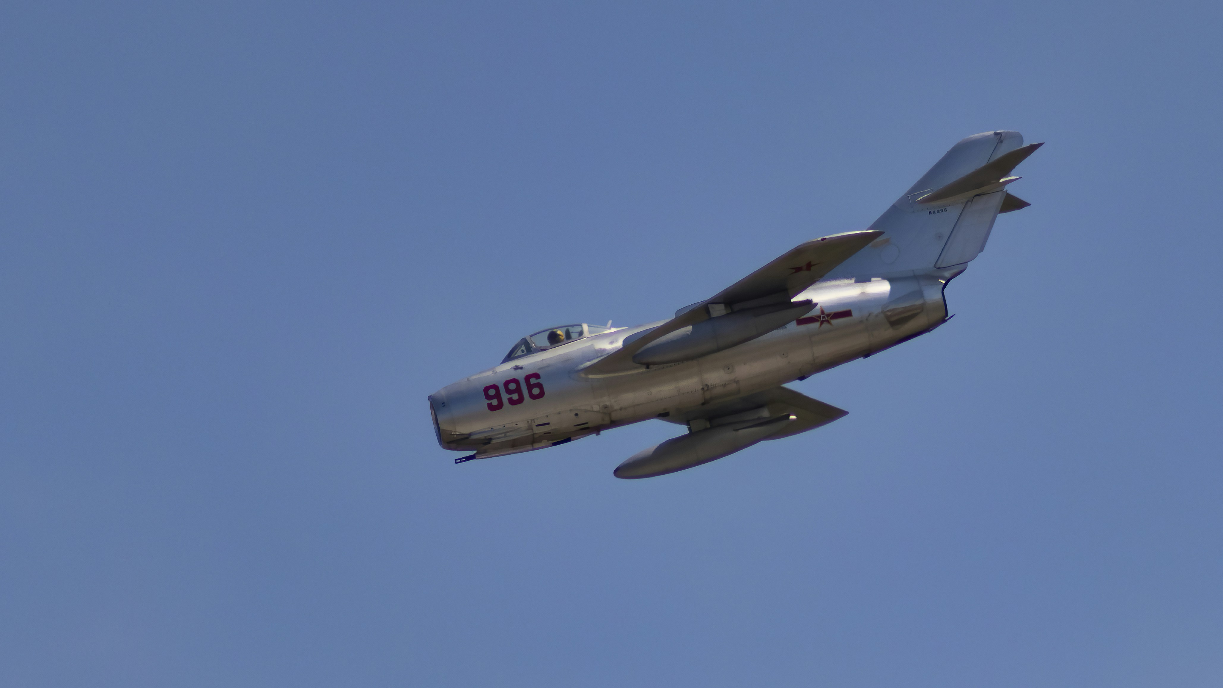 a silver airplane flying through a blue sky