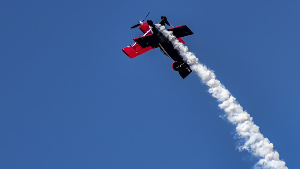 a red and black plane flying through a blue sky