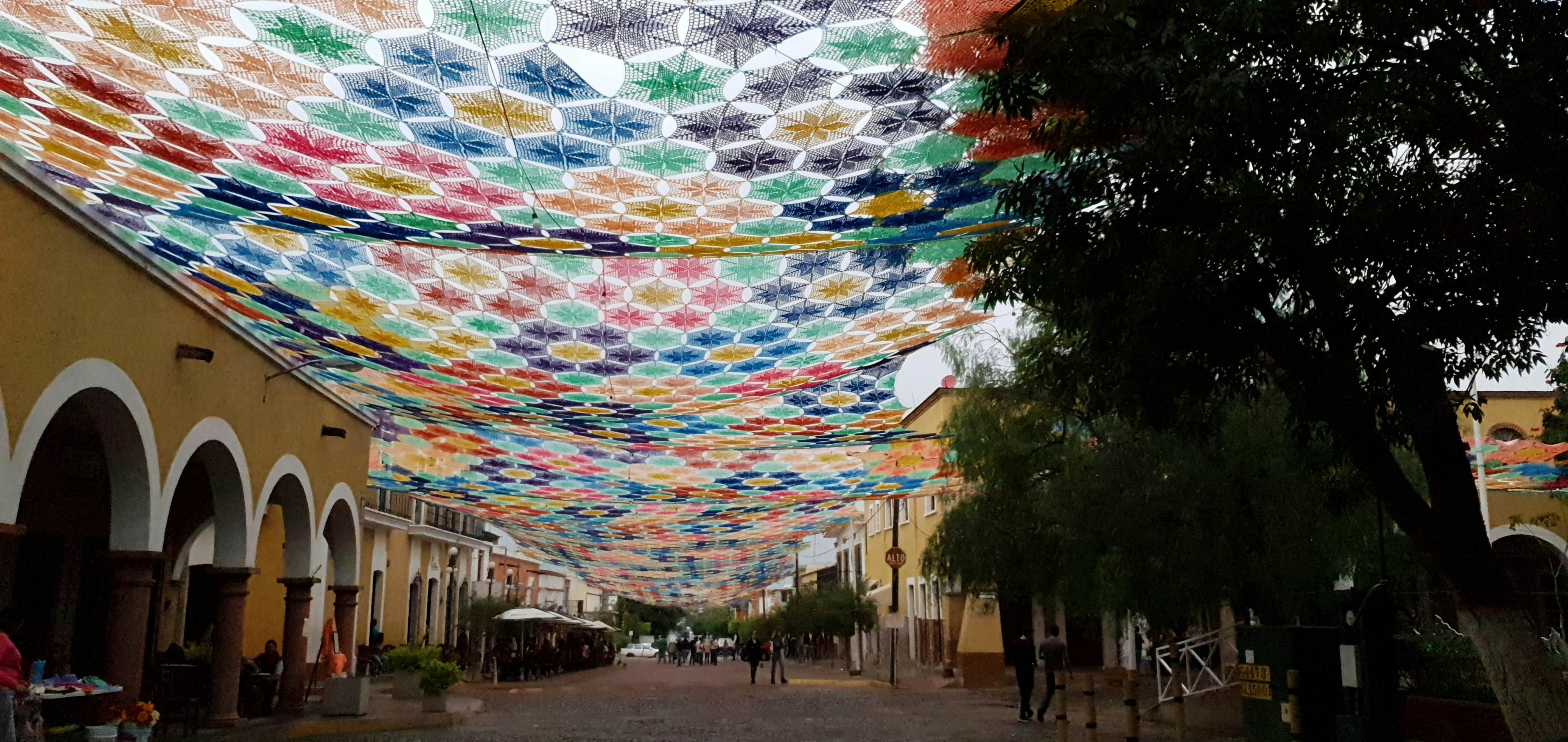 eine Straße, die von vielen bunten Regenschirmen gesäumt ist, die von der Decke hängen