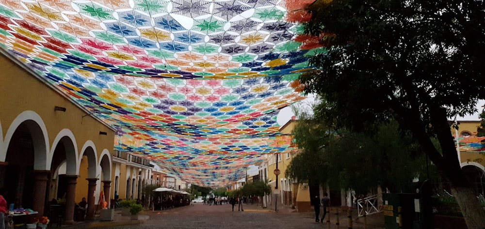a street lined with lots of colorful umbrellas hanging from the ceiling