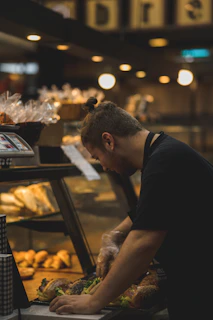 A chef preparing a quick gourmet sandwich behind the counter at γευστική πνοή.